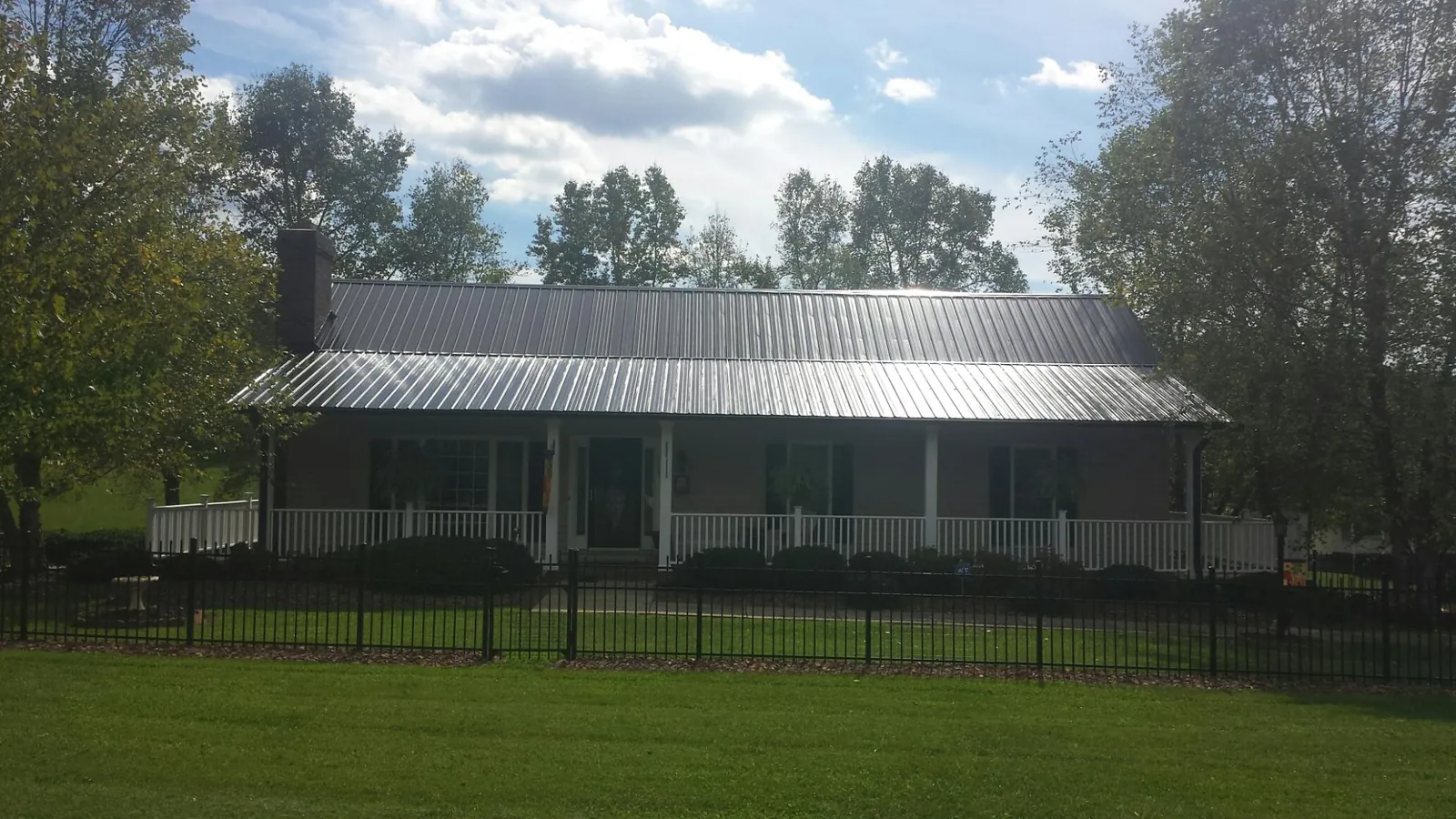 Gray metal roof on a brick ranch with a full width front porch — Gutter Guard Installation work by our crew in Willis